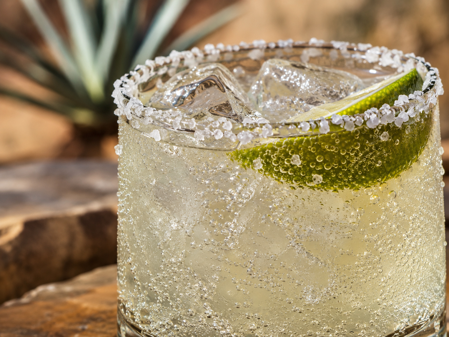 Close-up of the Mezcal Ranch Water showing salt crystals on the rim, ice, lime, and sparkling bubbles.
